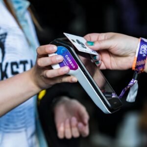 Person holding a credit card against a handheld payment terminal for a card payment.