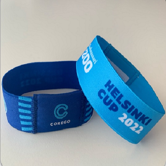Two blue silicone wristbands lying on a white surface; one reads 'HELSINKI CUP 2022' and the other shows a CoreGO logo.